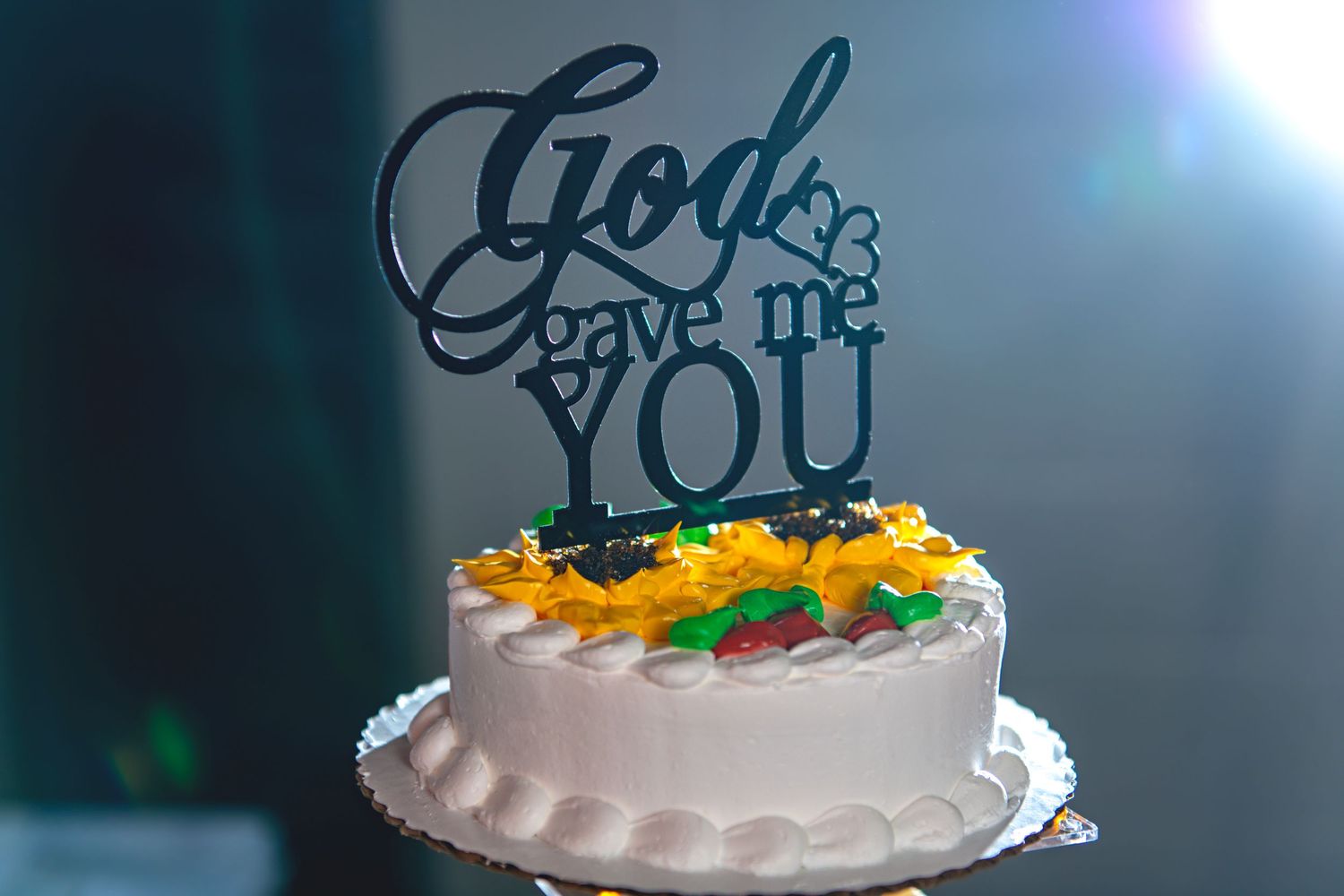 White wedding cake with colorful details topped with black acrylic God Gave Me You cake topper.