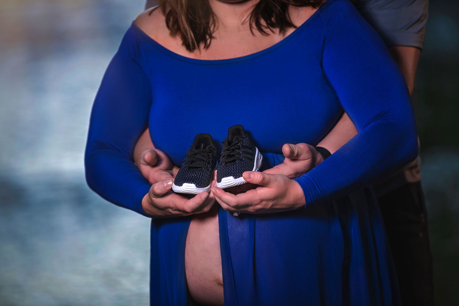 maternity photo with baby shoes couple