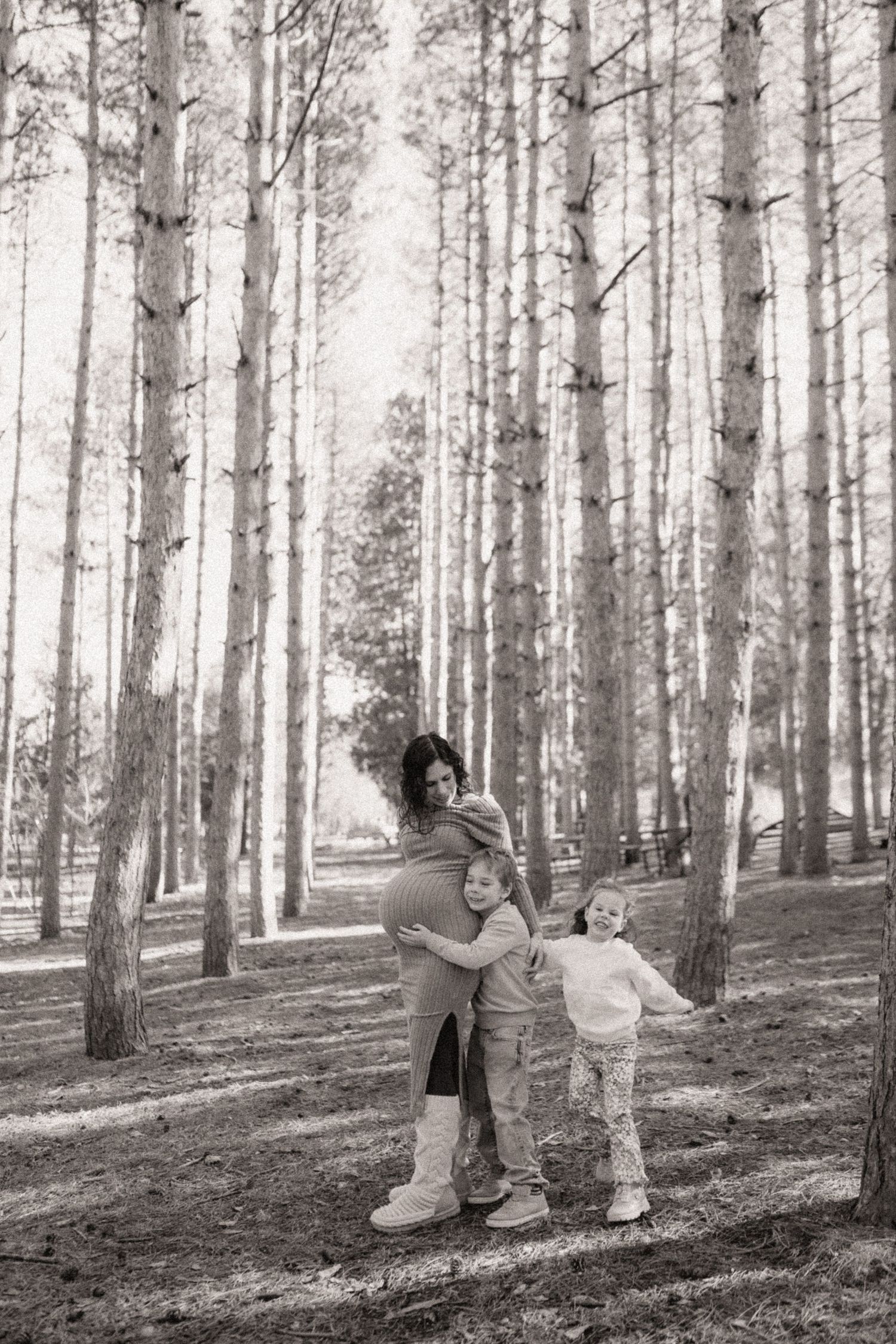 Black and white photos of people playfully posing in a serene pine forest setting.