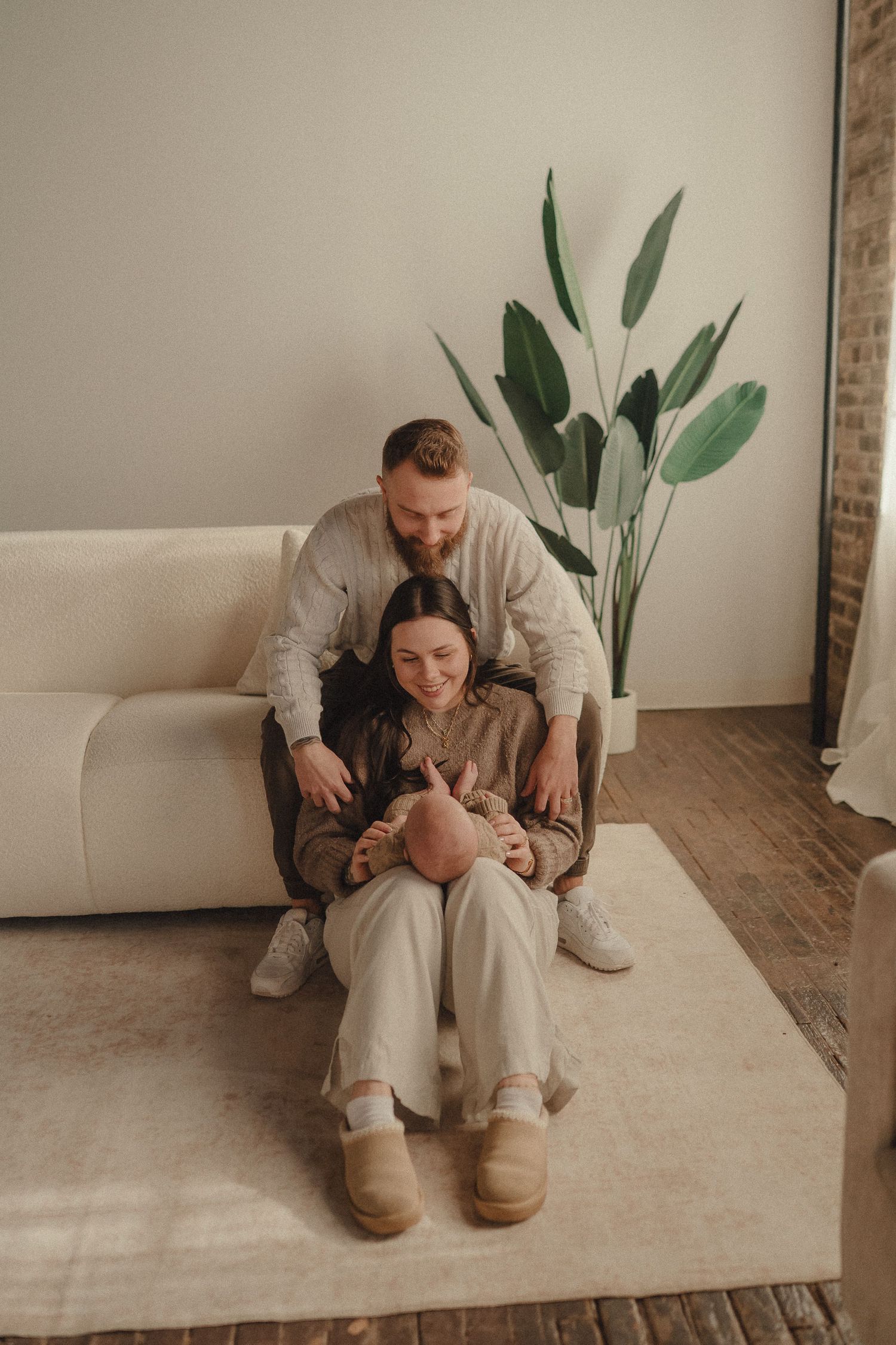 Couple sitting together on a white couch in a minimalist room with plants.