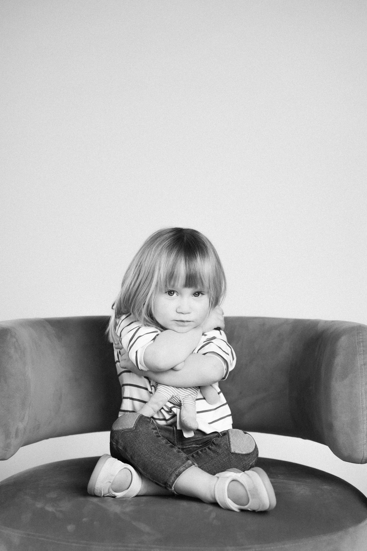 Black and white photo series showing a small child sitting on a couch in casual clothing.