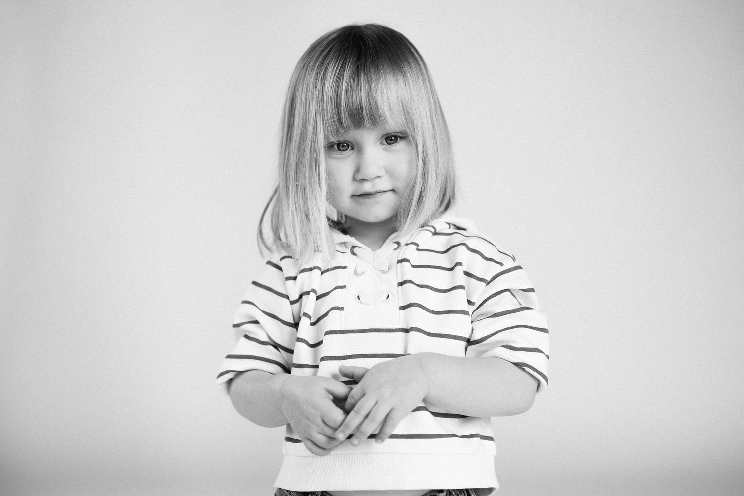 A series of black and white portraits showing a small child in a striped shirt making different expressions.