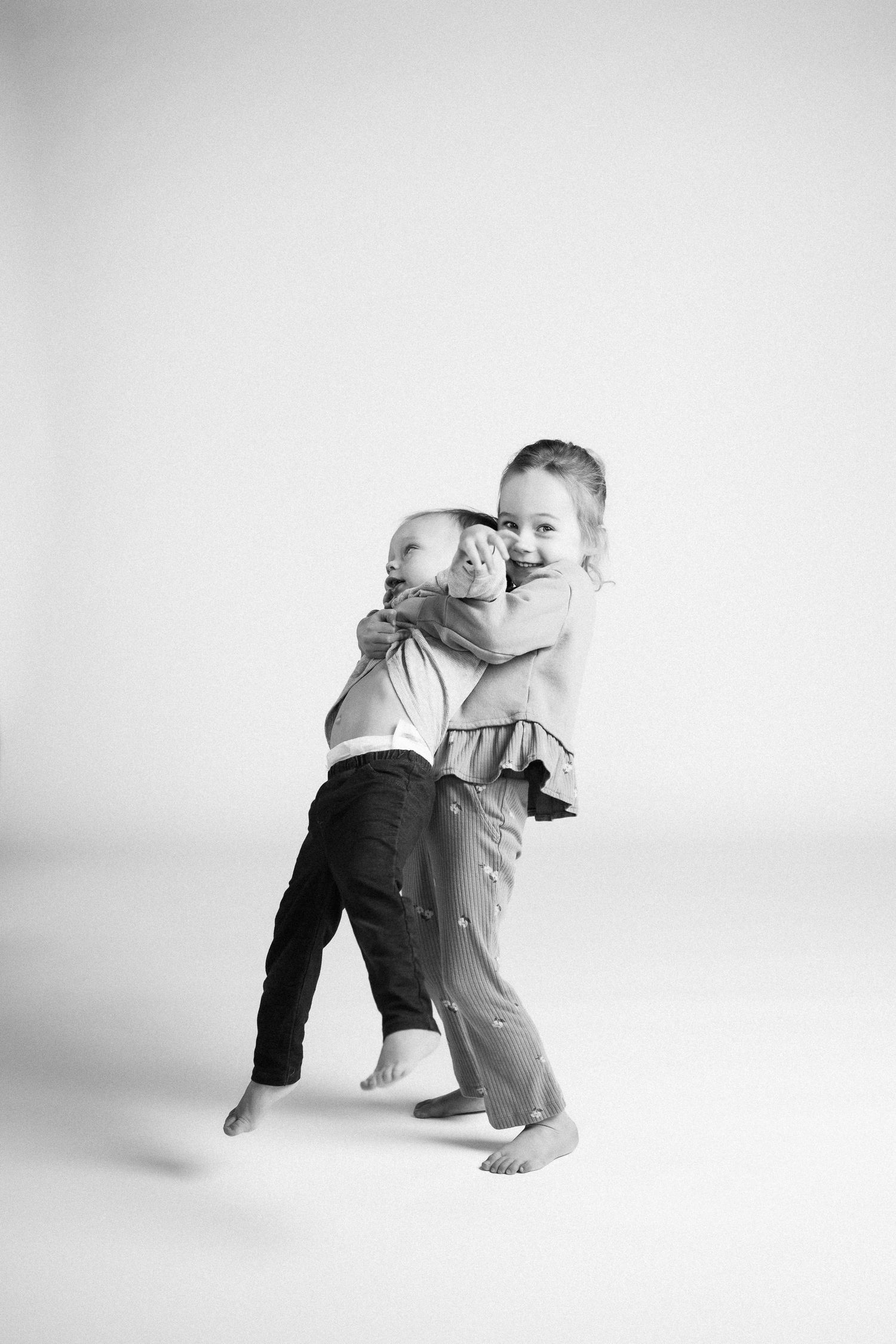 Black and white photo series showing dynamic movement and interaction between two people in white studio setting.