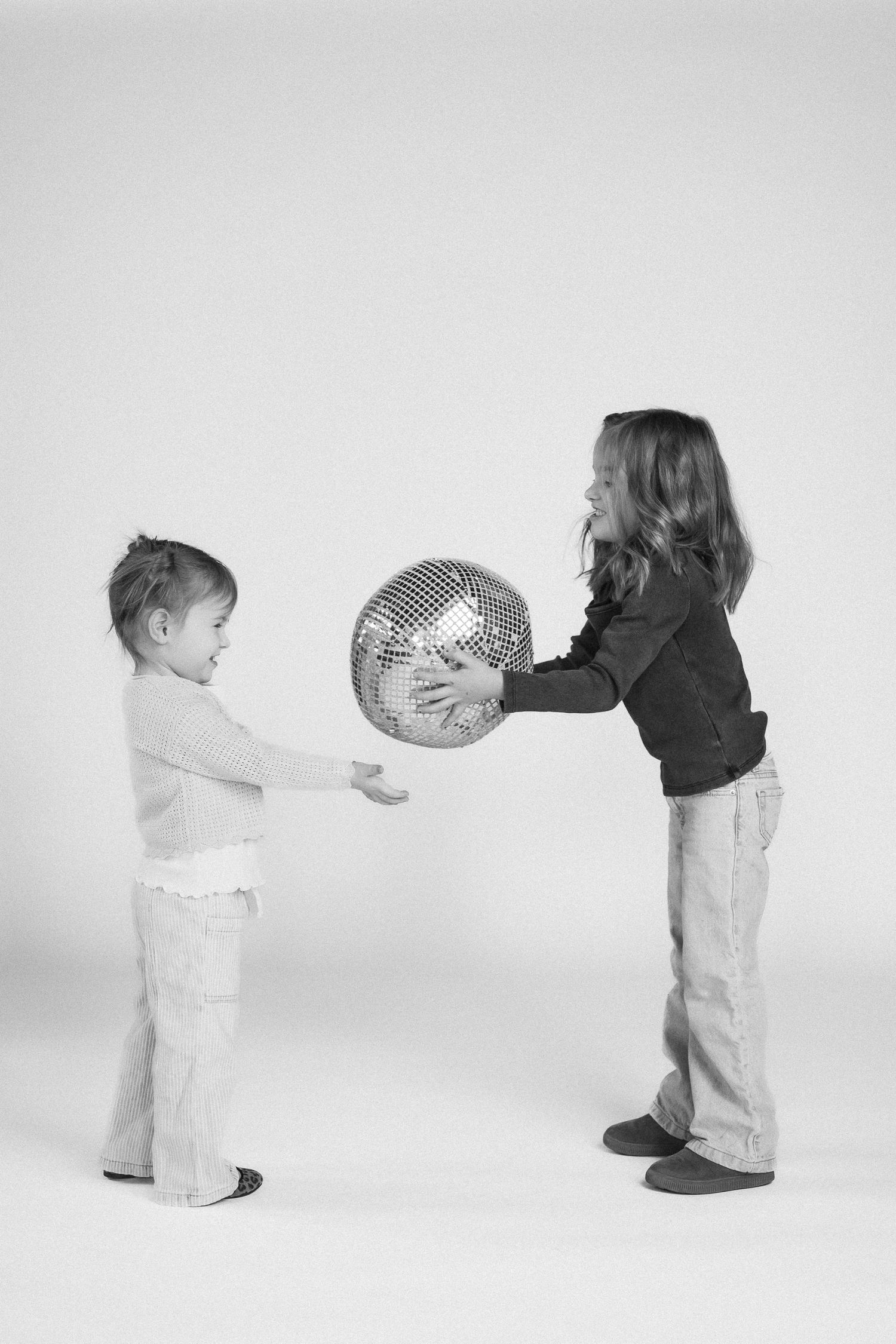 A sequence of black and white photos showing two children passing a ball back and forth in a playful interaction.