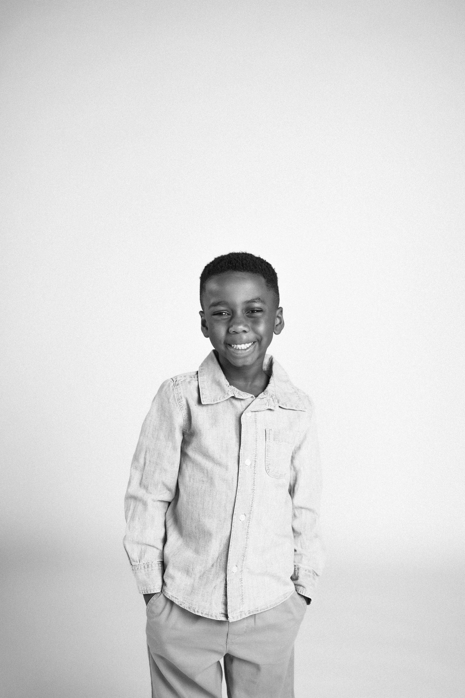 A child in a light colored button-down shirt poses against a white background.