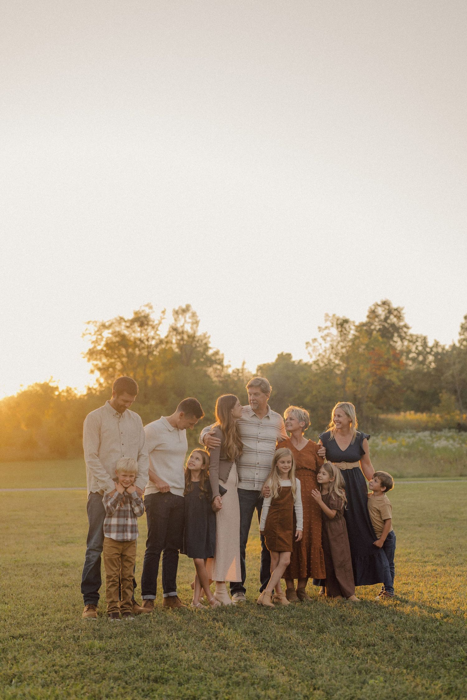 Group portrait in a golden field at sunset with warm lighting and natural scenery.