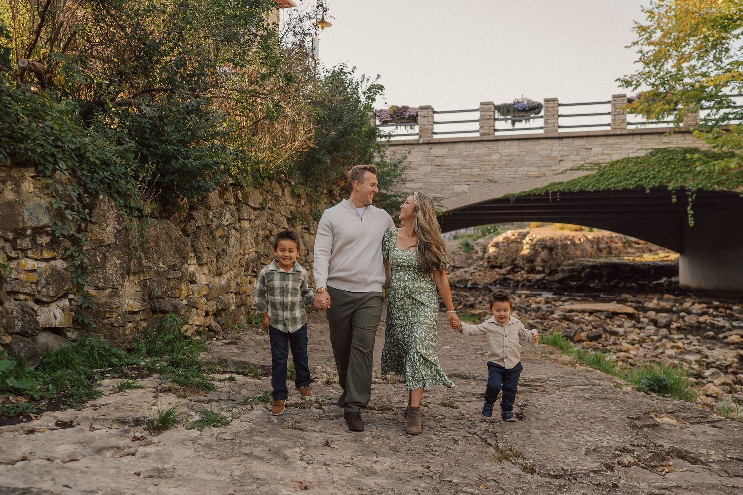 Group photo session under a rustic stone bridge with natural scenery.