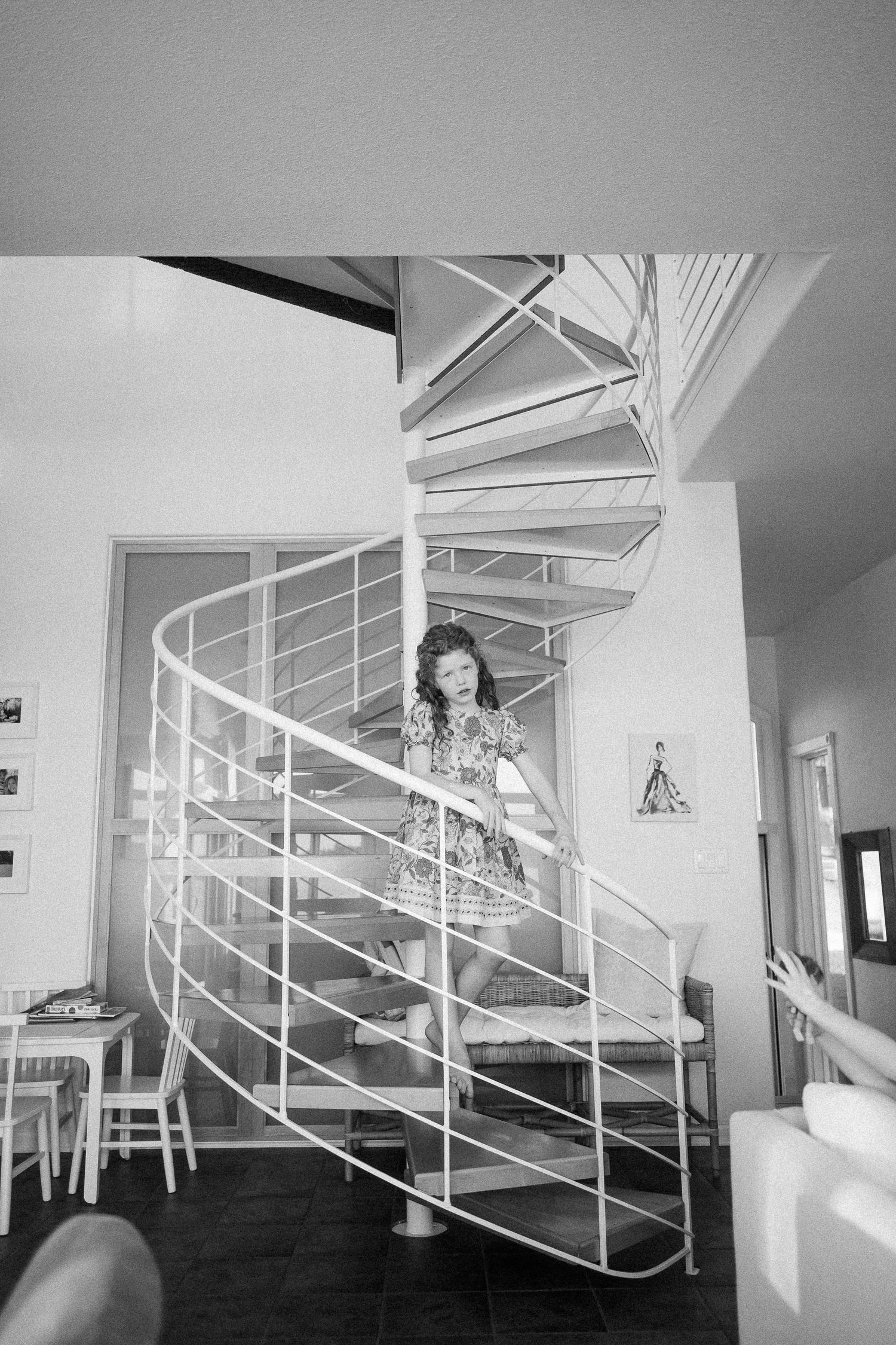 A sequence showing movement down a modern white spiral staircase in black and white photography.