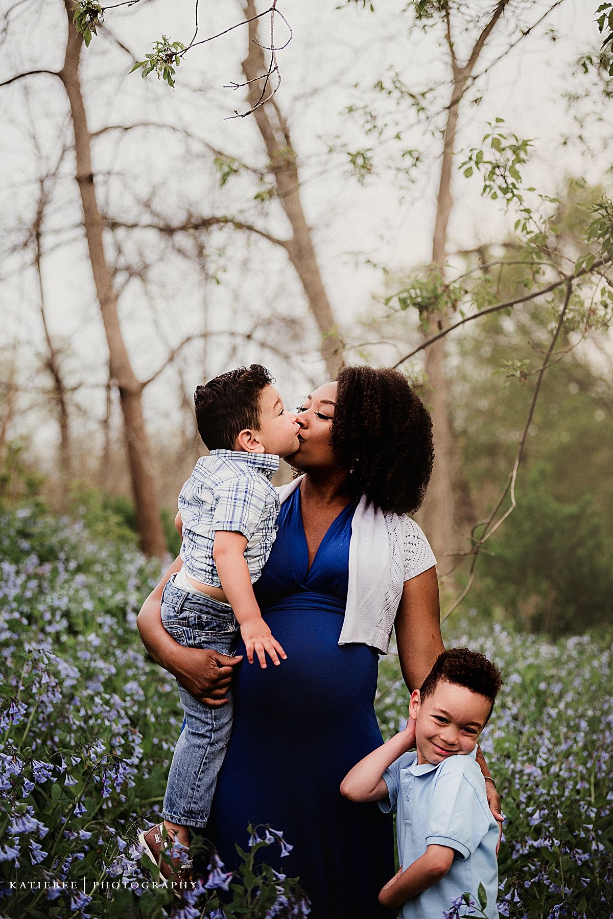 Beautiful outdoor family portrait with mother and children surrounded by purple wildflowers.