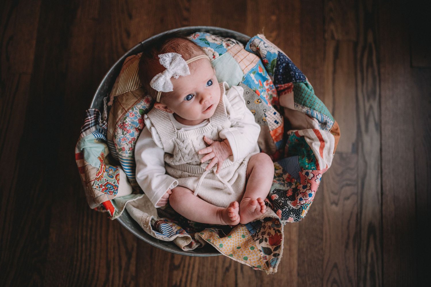 Overhead view of an infant in white clothing nestled in a floral patterned bowl.