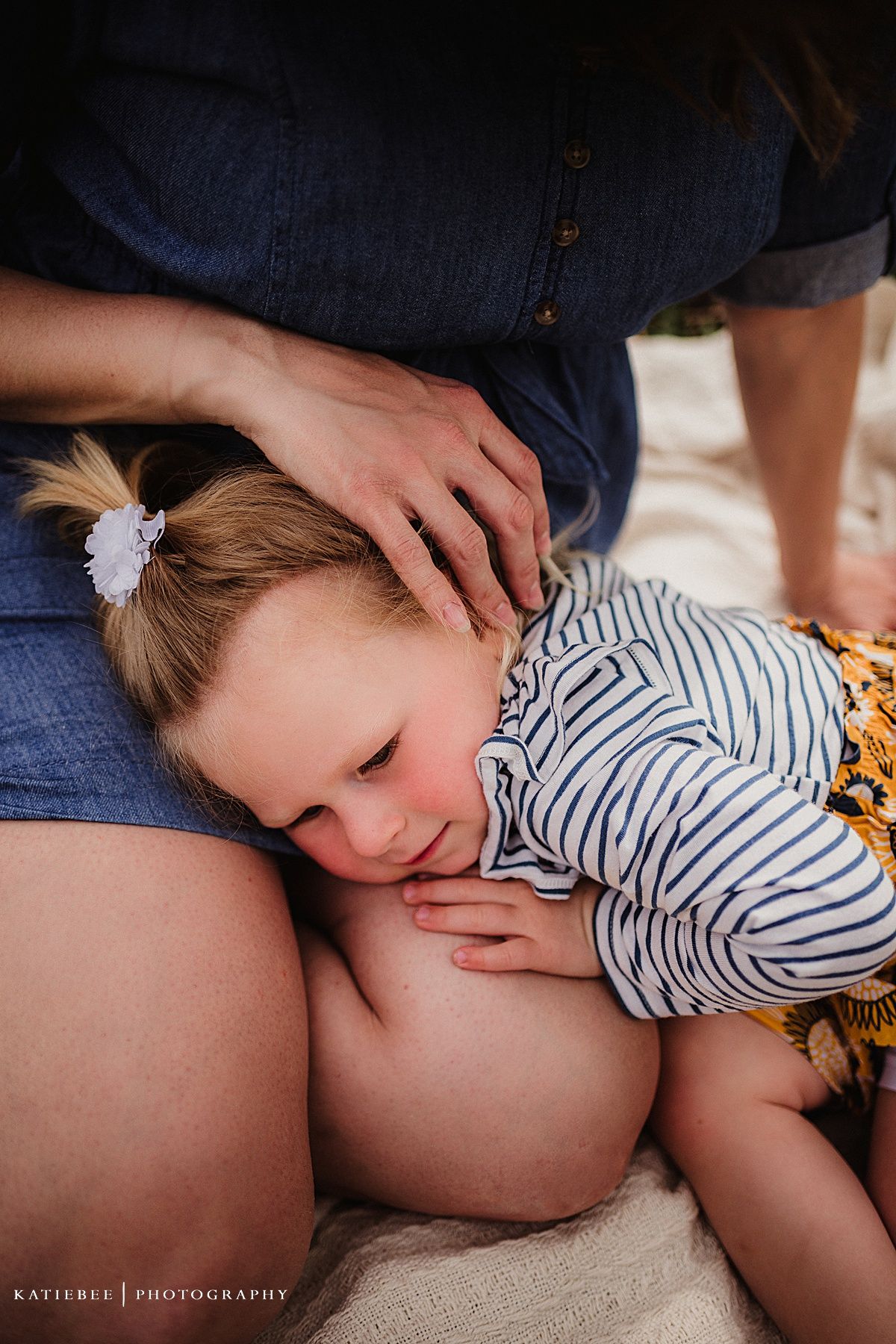 An intimate quiet moment between two people resting together on a blanket outdoors.