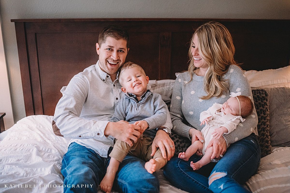 Indoor lifestyle portrait of a relaxed family with young children on a bed.