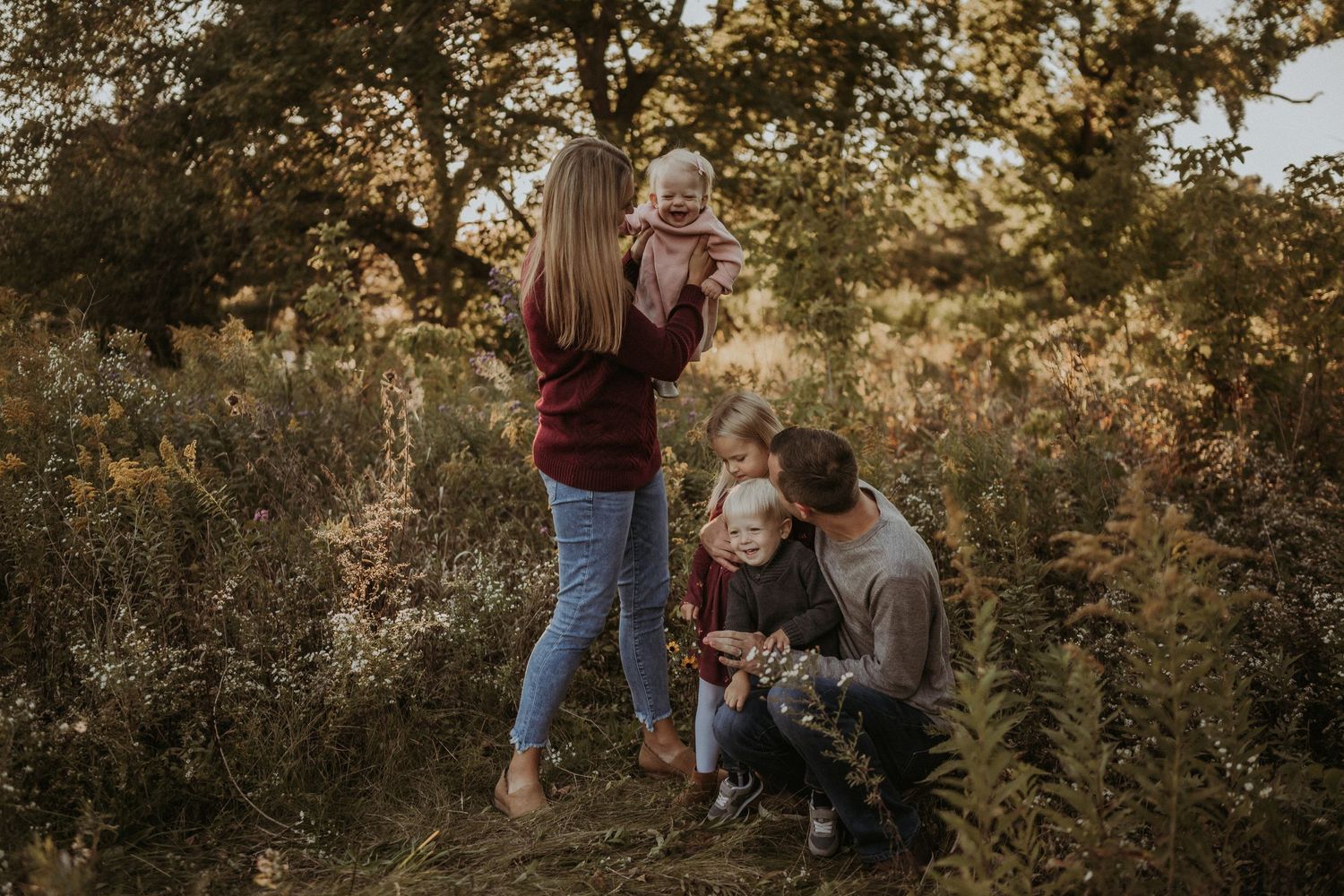 A family shares a tender moment together in a wild meadow at sunset.