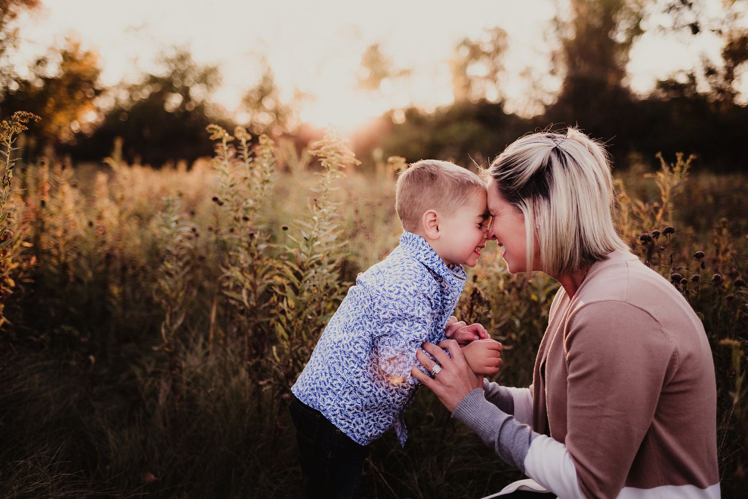 Sweet interaction between adult and child outdoors in field during sunset.