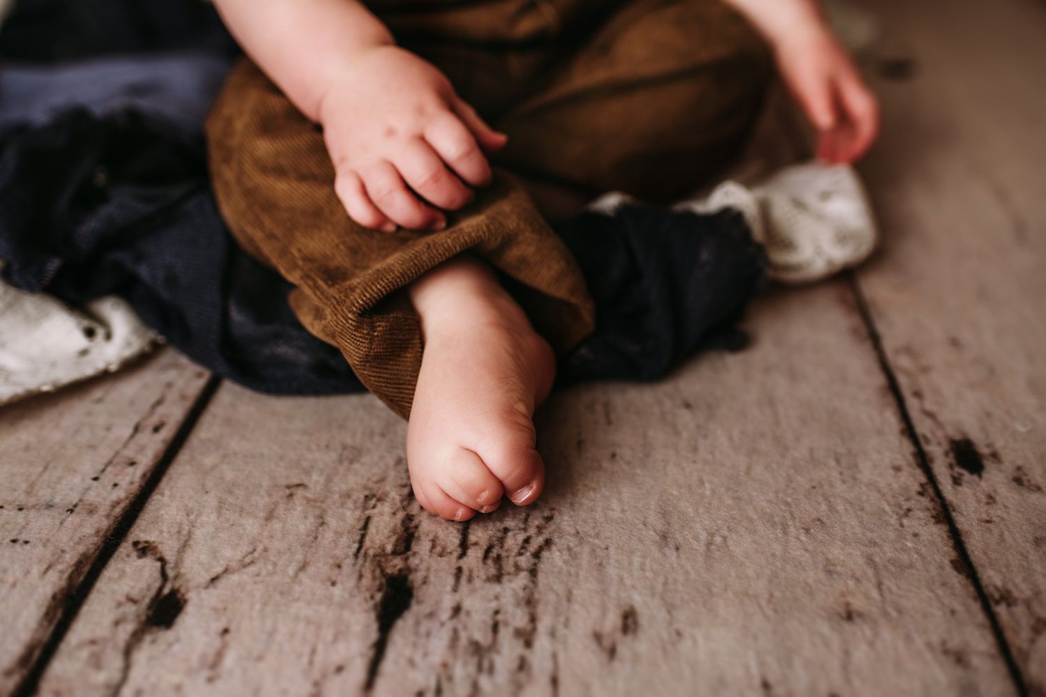 Close up of bare feet on wooden floor with brown and navy fabric.
