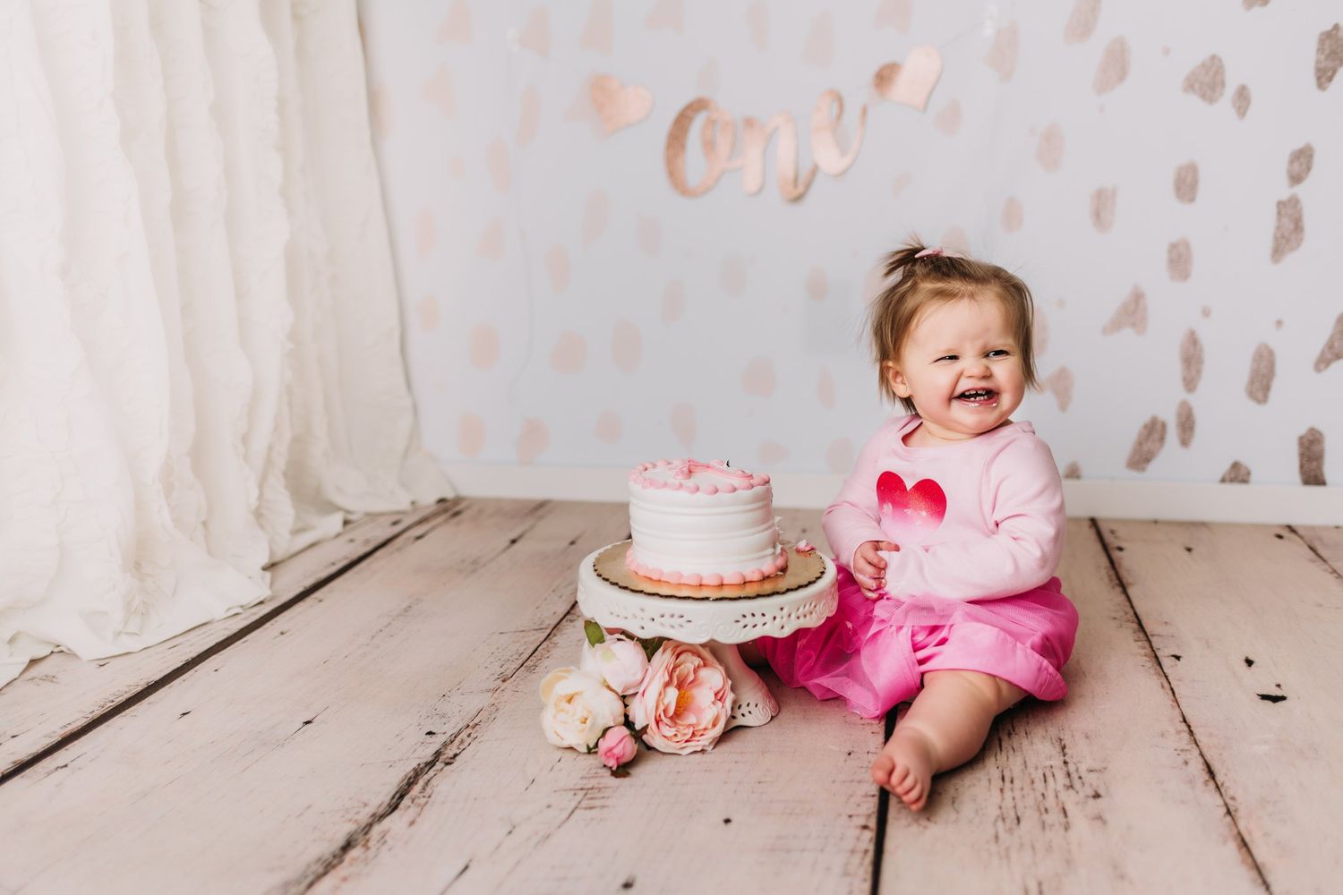 Joyful celebration scene with small cake and pink outfit against textured backdrop.