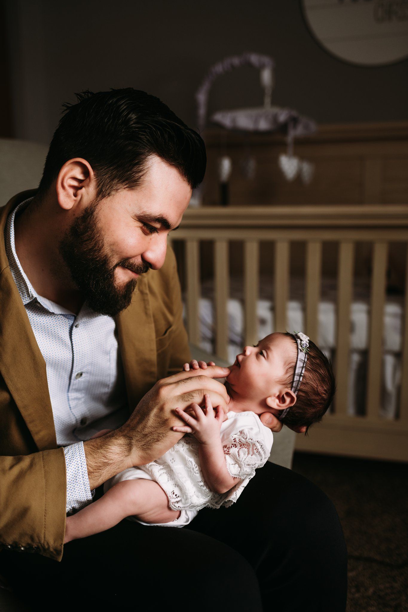 Tender moment between caregiver and baby in nursery with crib.