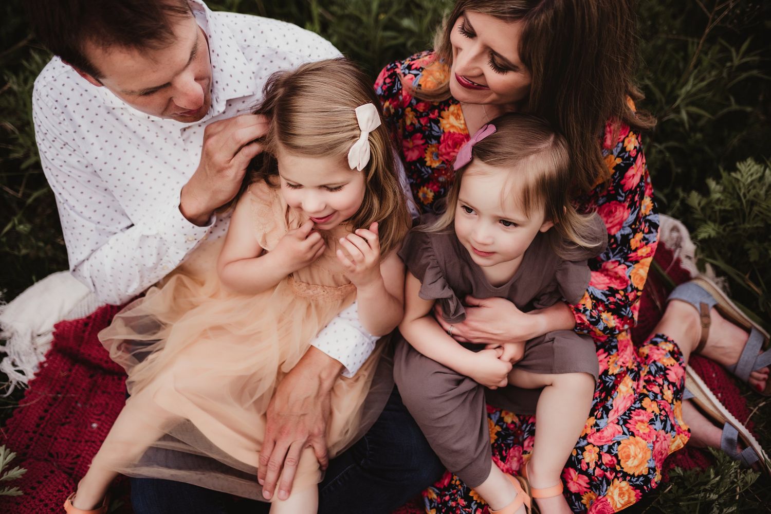 A cozy family portrait on a red blanket showing tender moments of connection.