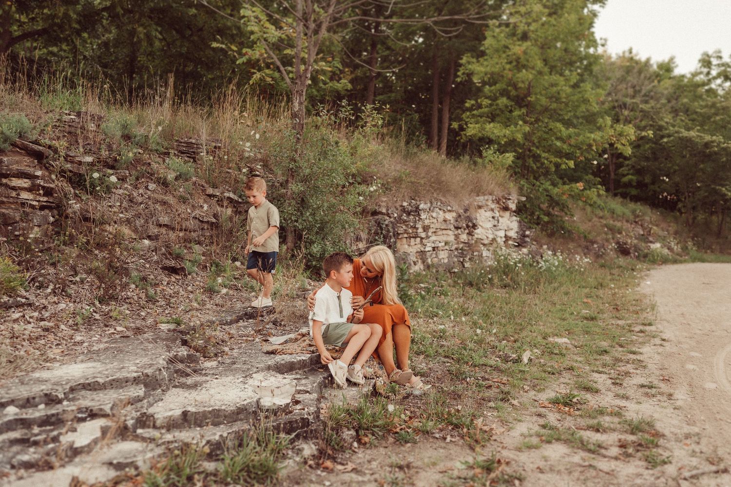 A tender family moment captured on weathered stone steps in a natural outdoor setting.