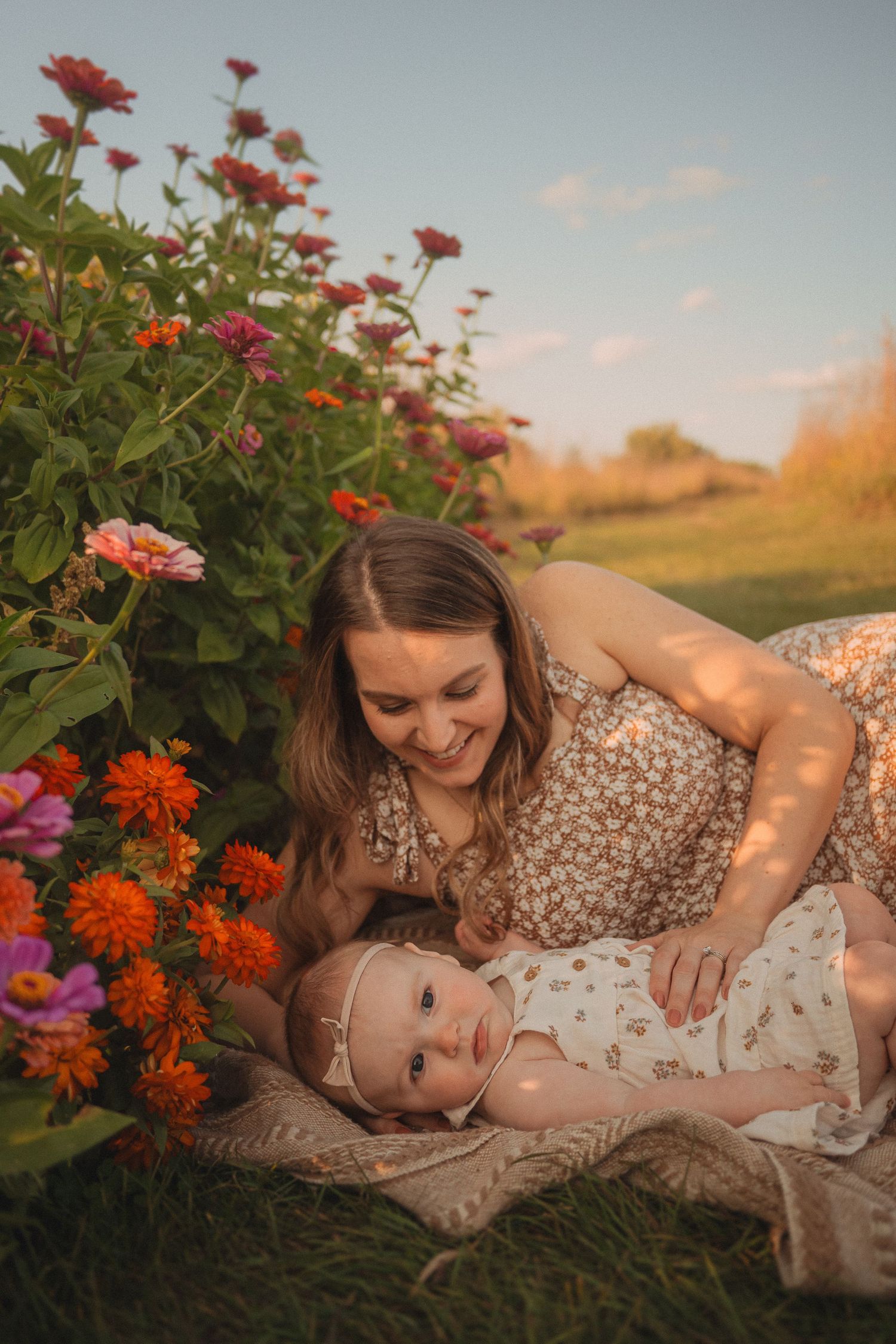Peaceful sunset garden scene with floral dress on blanket among blooming zinnias.
