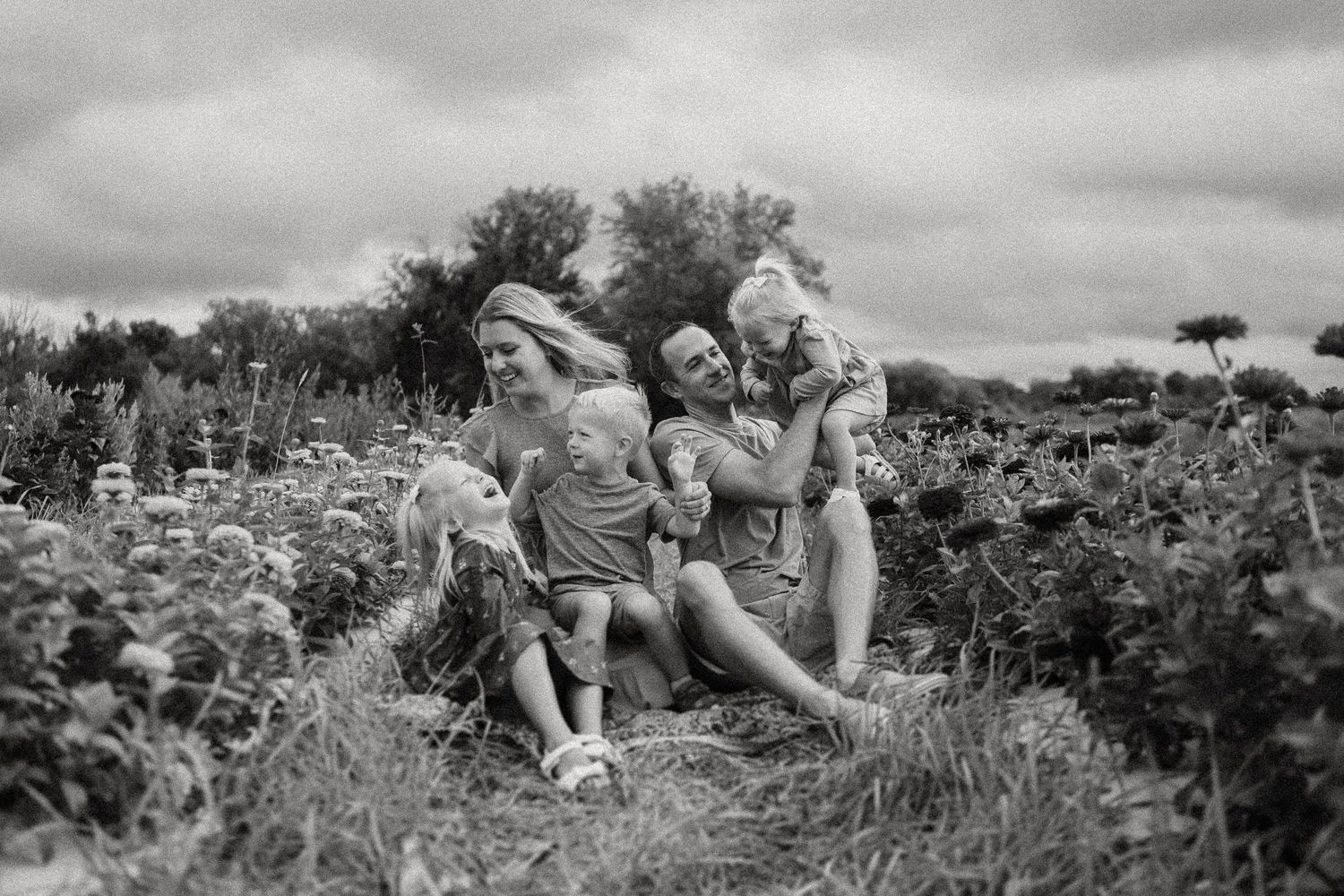 Black and white candid photo of a group enjoying themselves in a flowering field.