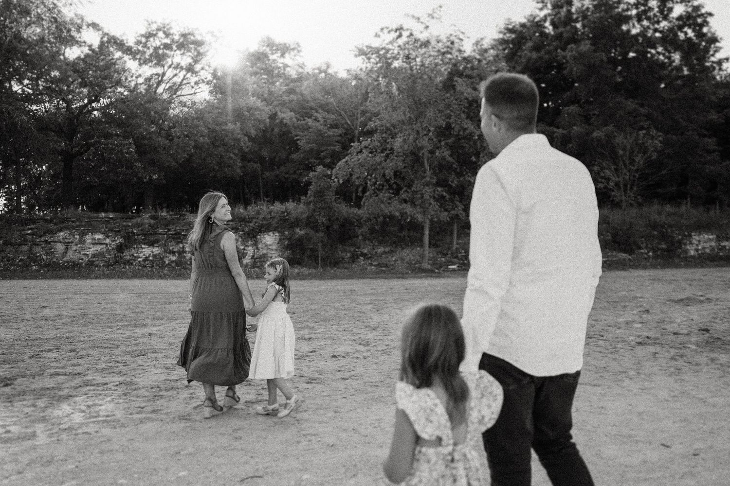 A family in casual attire stands together in an open field at sunset.