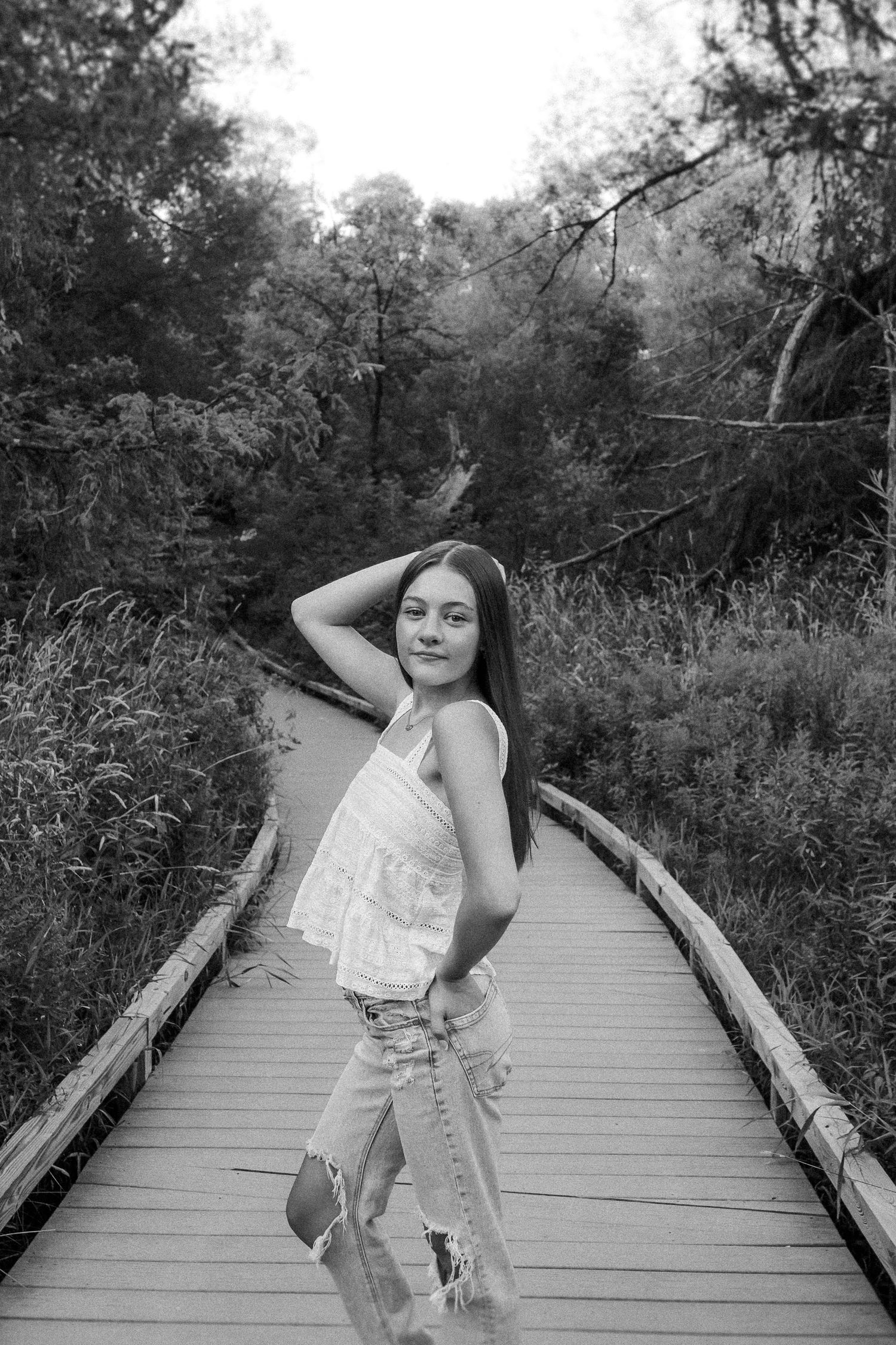 Black and white sequence of someone posing on a wooden boardwalk surrounded by natural vegetation.