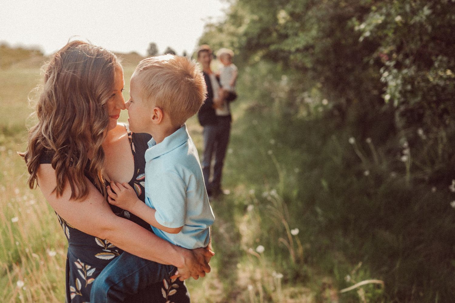 A loving moment captured between parent and child against a natural outdoor backdrop.