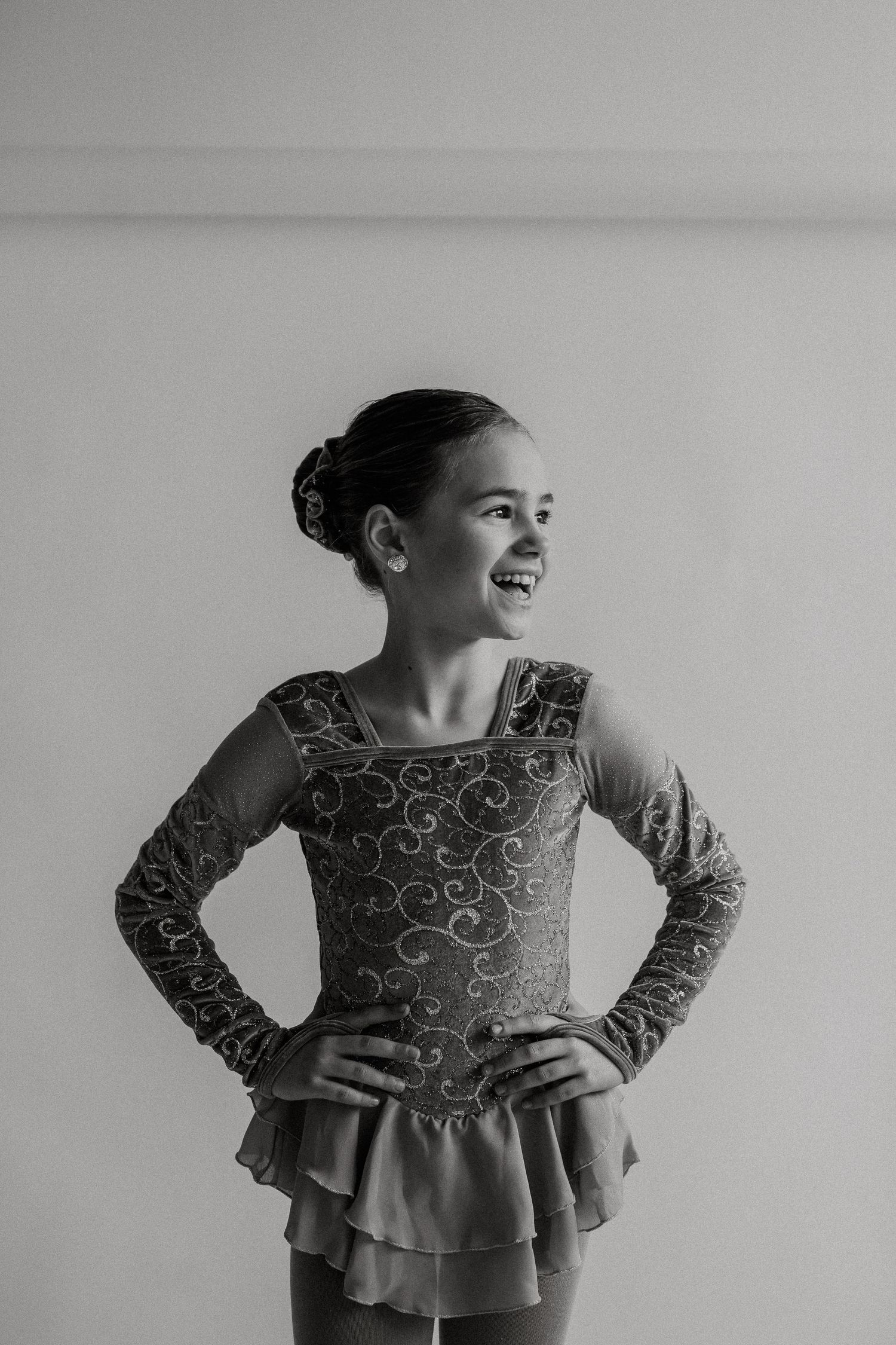 Black and white portrait of figure skater in ornate performance dress posing elegantly.