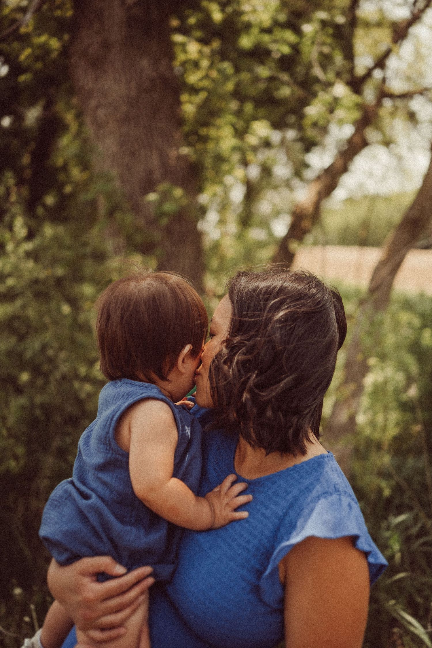 A sweet embrace between parent and child wearing matching blue outfits outdoors.