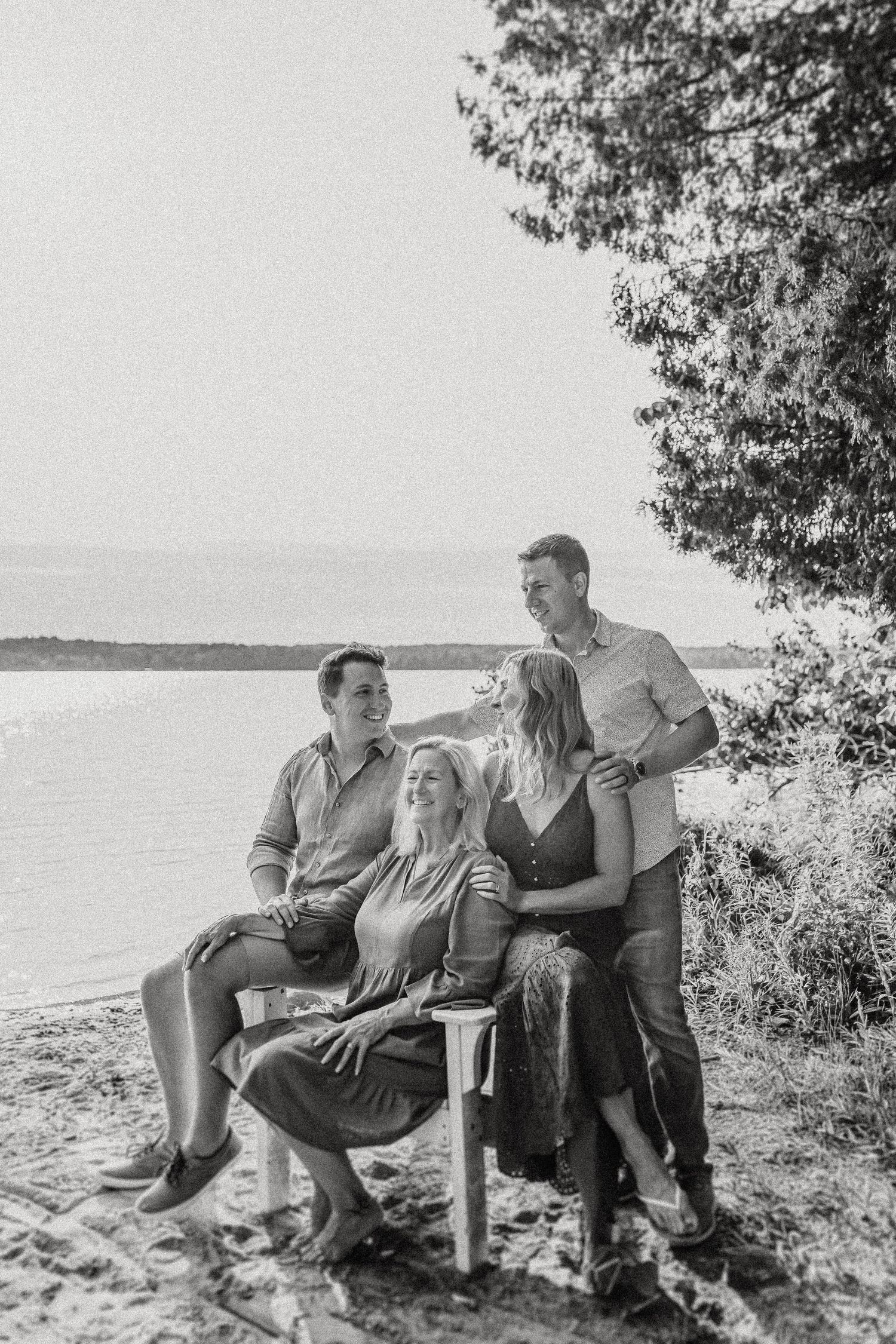 Black and white portrait of a group gathered on chairs at a waterfront location.