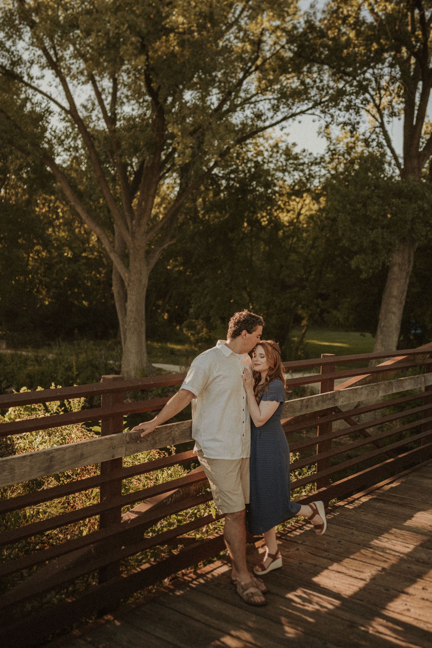 Romantic sunset moment on a wooden bridge surrounded by trees.