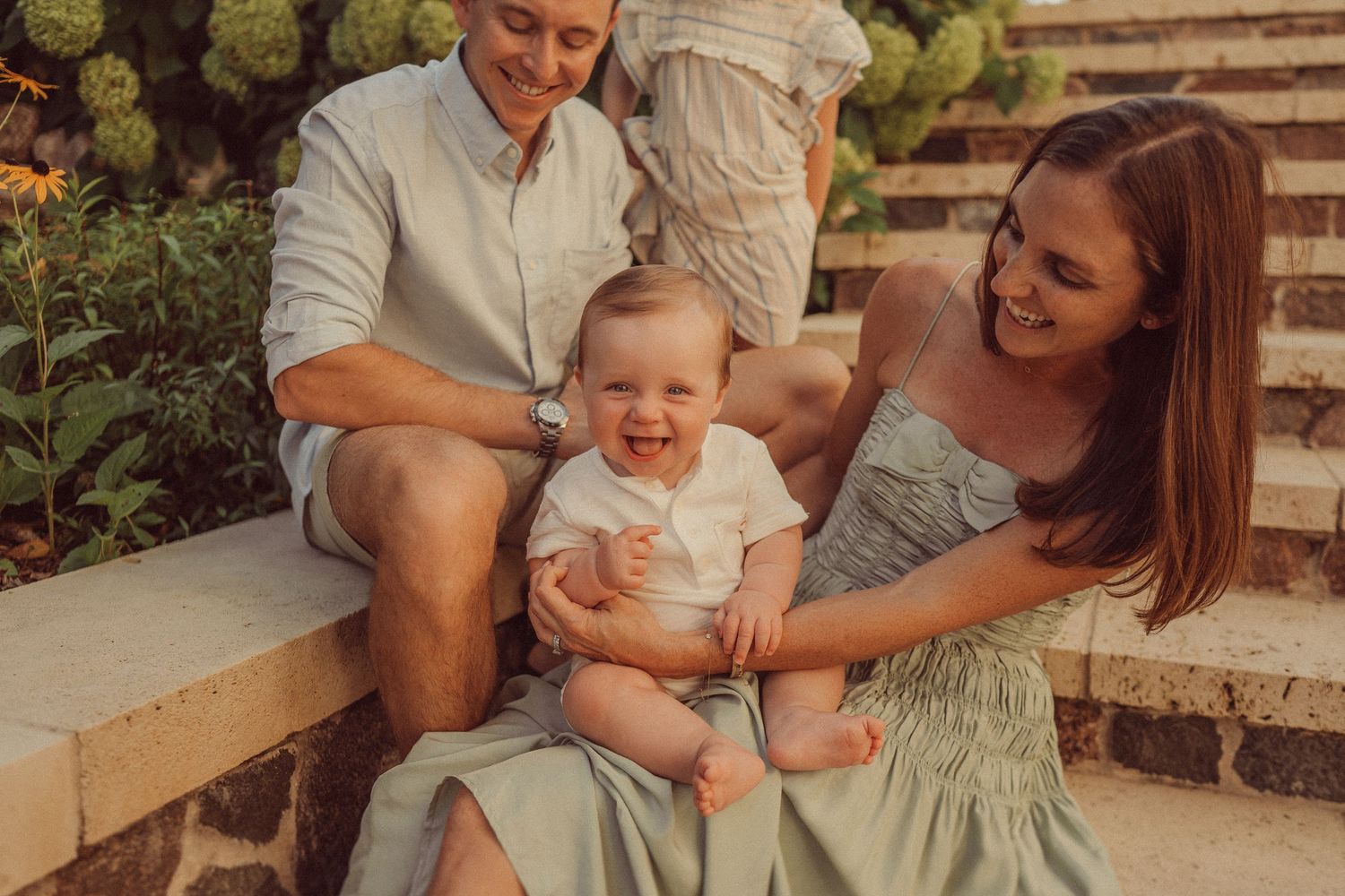 Warm-toned photo of a family sharing a happy moment on stone garden steps.