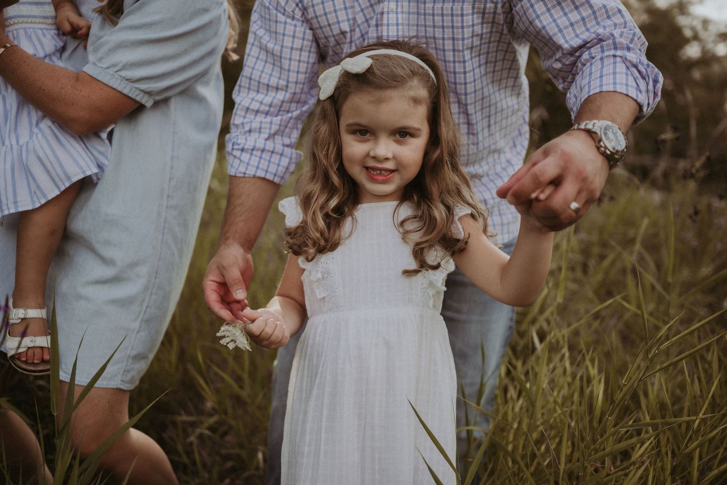 A candid portrait of a family moment in a sun-drenched field.
