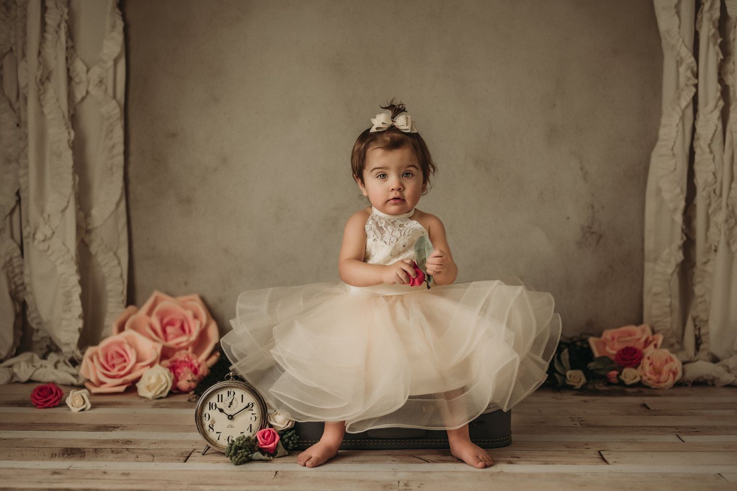 Elegant portrait setup with pink floral decorations and vintage timepiece.