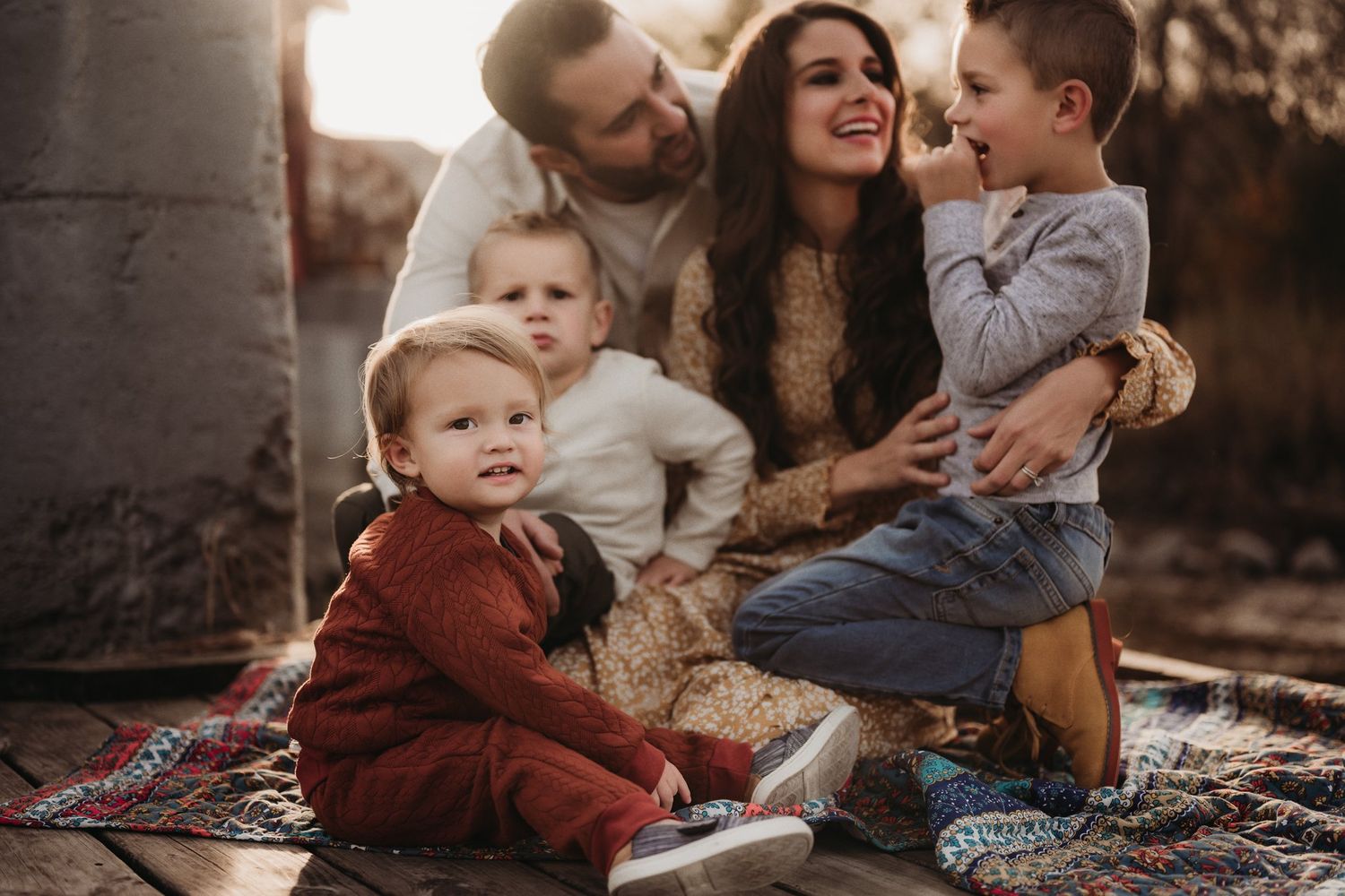 Candid family moment shared on a blanket during sunset outdoors.