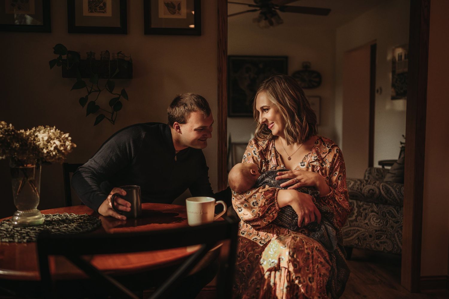 Warm-toned photograph of couple sharing intimate moment at dining table with coffee.