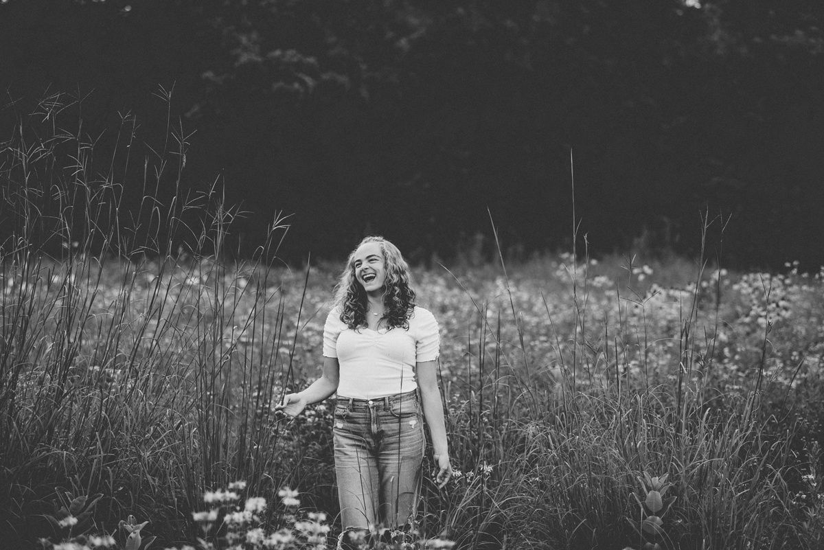 Black and white portrait in a meadow with tall grasses and flowers.