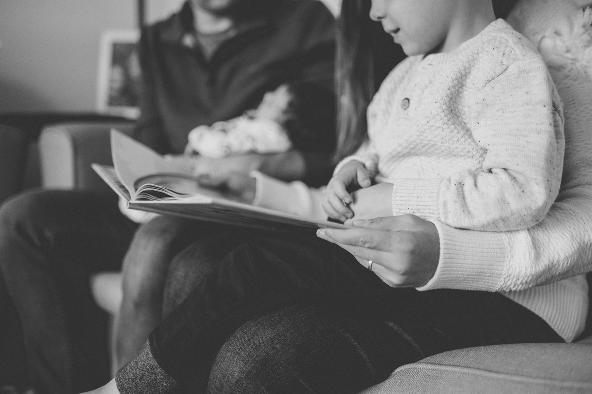 Family members reading together in black and white on comfortable couch.