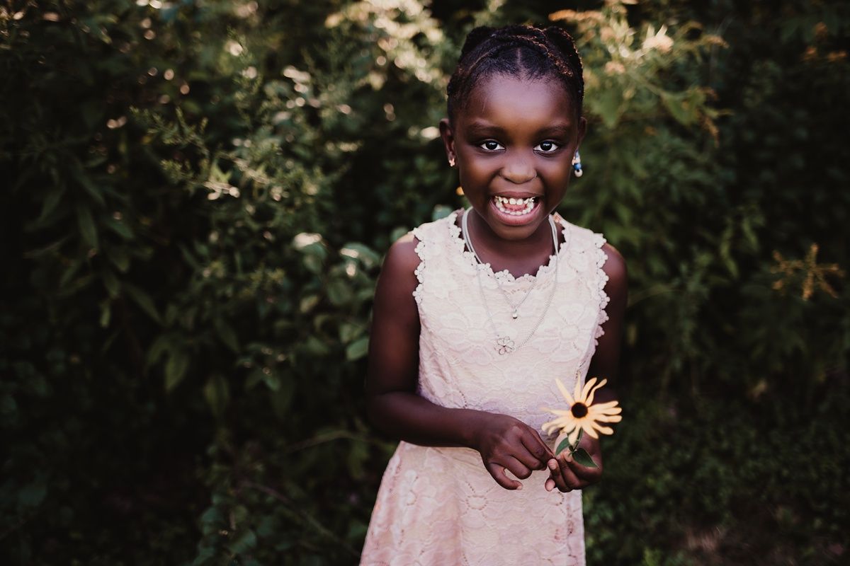 A bright and cheerful moment captured while holding a delicate flower in a garden setting.