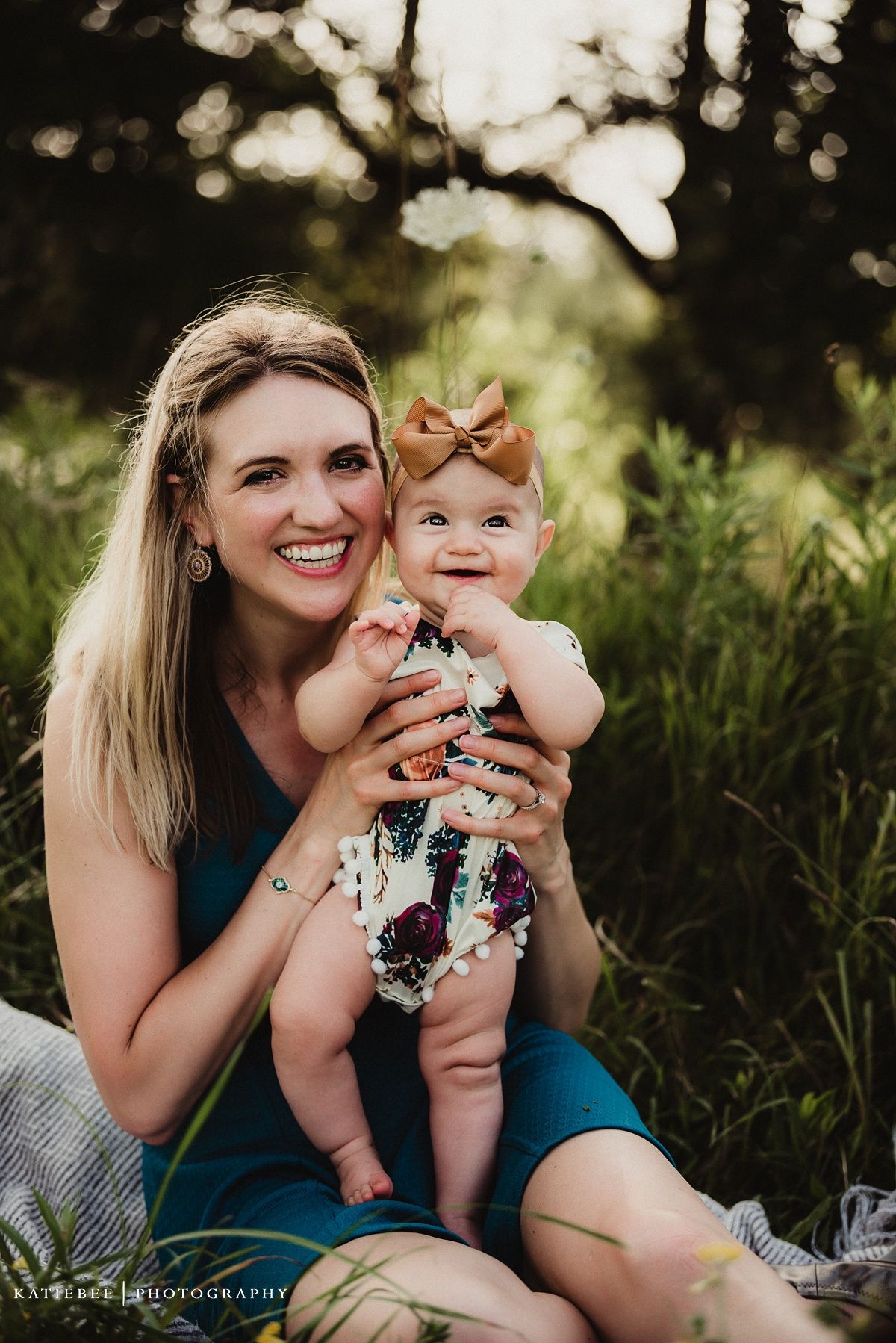 Candid outdoor portrait of mother and baby sharing joyful smiles in natural setting.