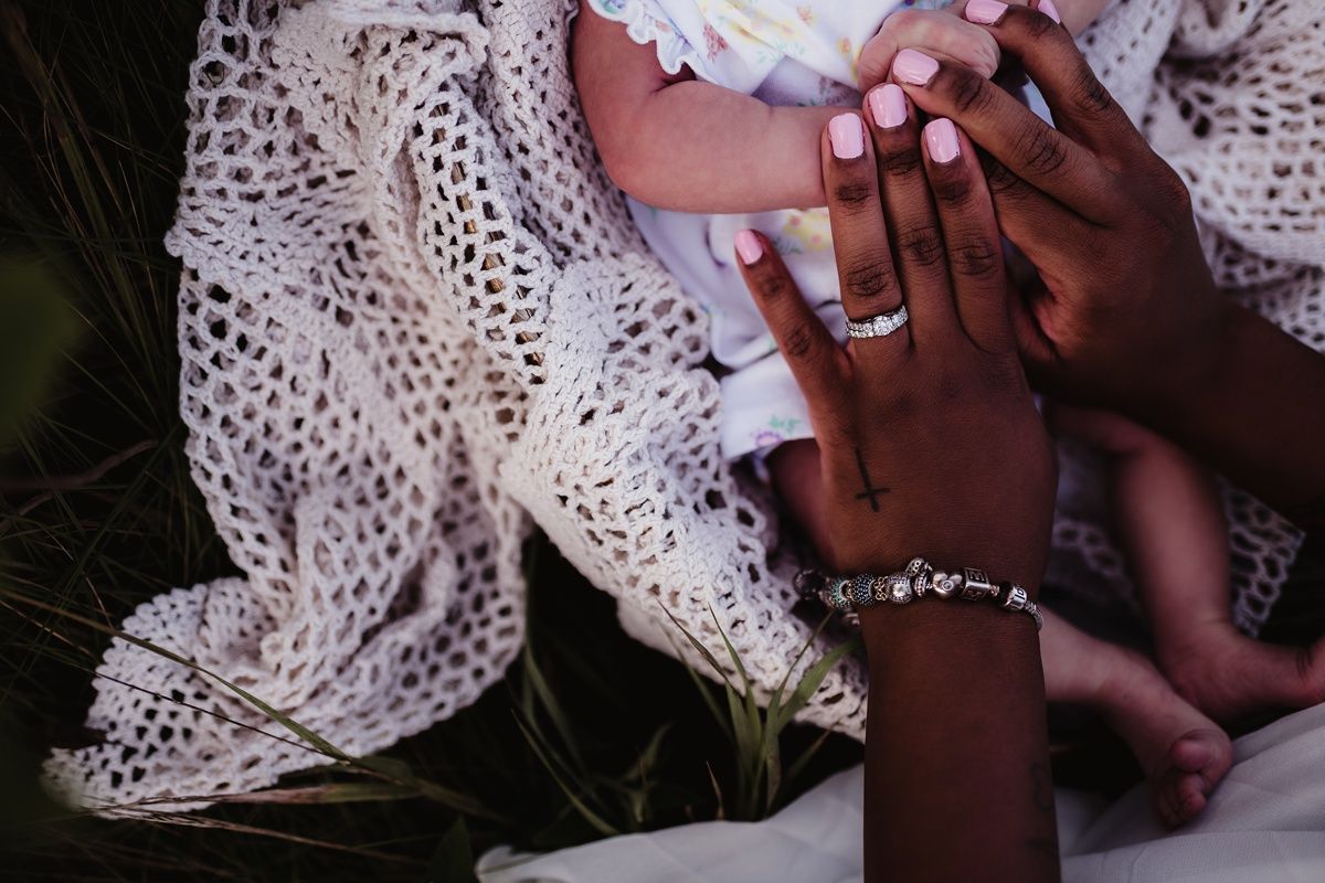 Close-up shot of hands wearing delicate white lace and jewelry in soft lighting.