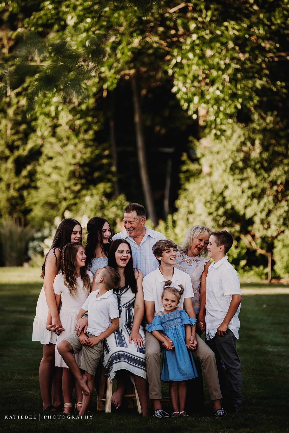 A multi-generational outdoor photoshoot with a group wearing coordinated white and blue outfits.