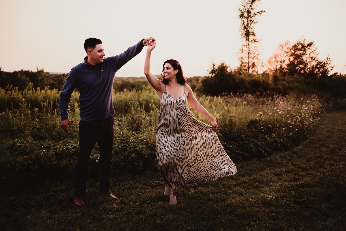 Couple dancing together in a wildflower field at sunset.