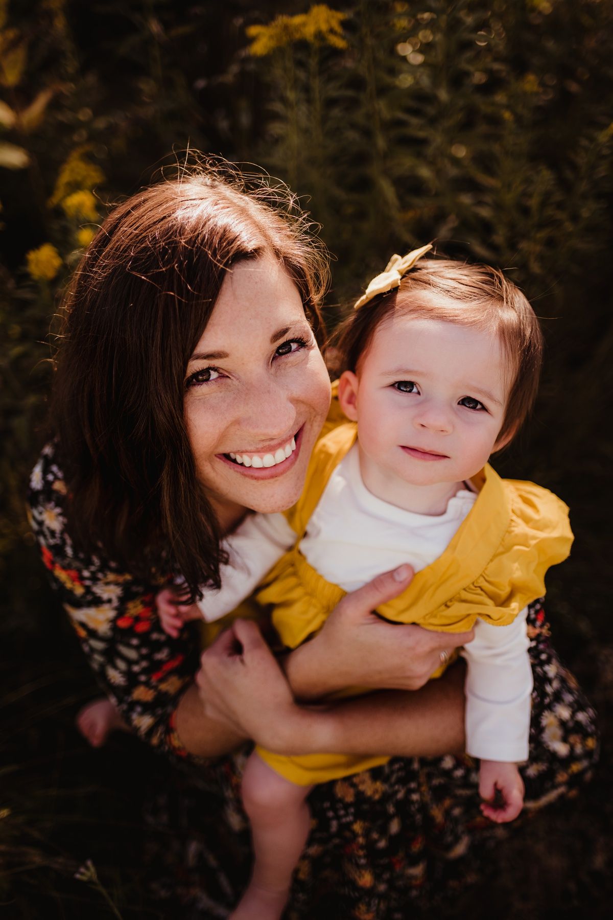 An intimate close-up moment between adult and toddler in yellow against a natural backdrop.
