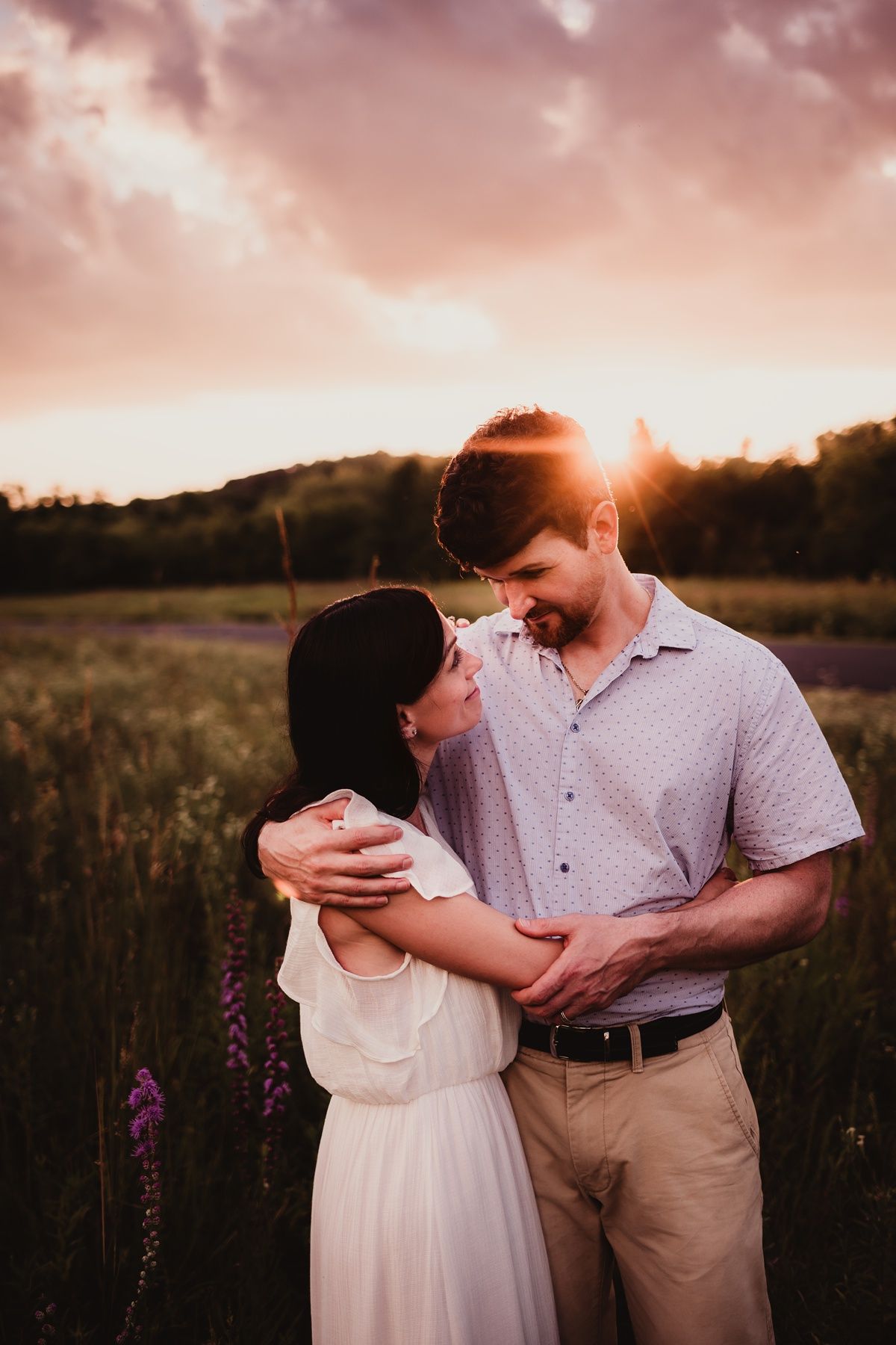 A romantic sunset portrait in a field with wildflowers and warm lighting.