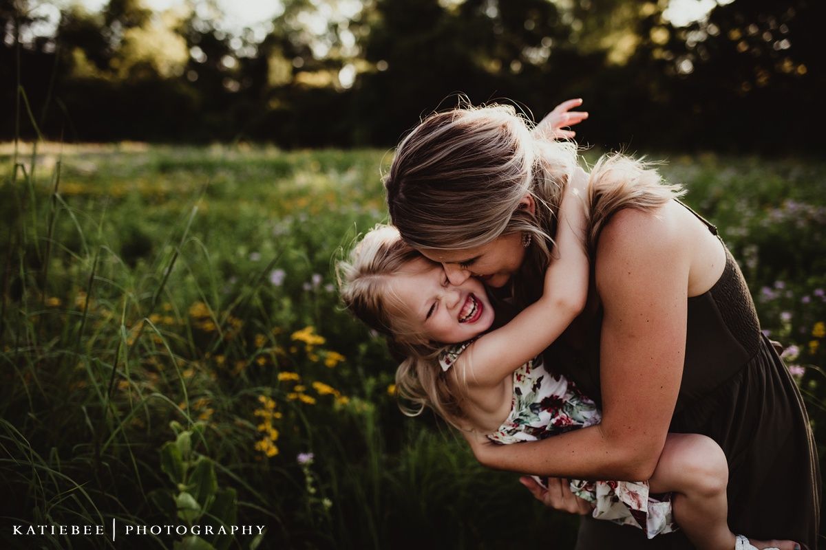 Joyful outdoor portrait showing playful interaction amidst a field of wildflowers at sunset.