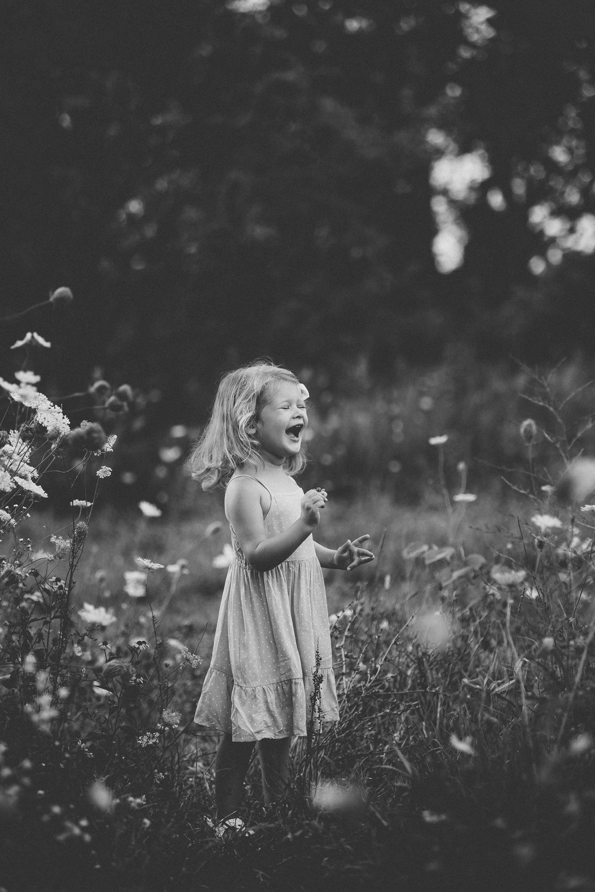 A joyful moment captured in black and white as a child plays in a wildflower meadow.