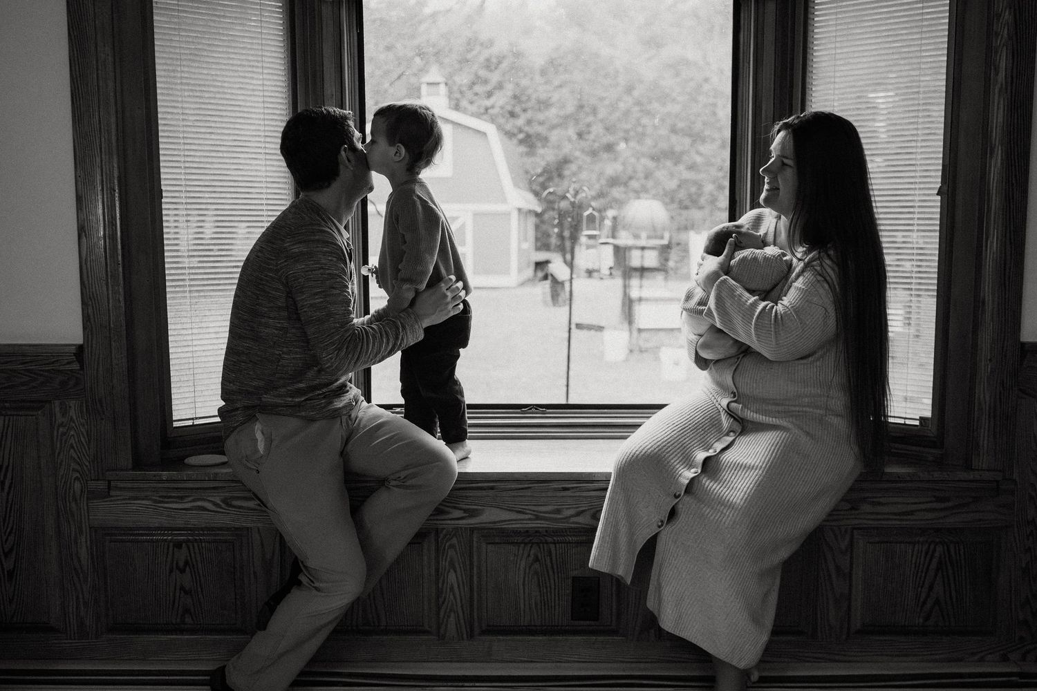 Silhouetted figures share intimate moments by large windows in dramatic black and white.