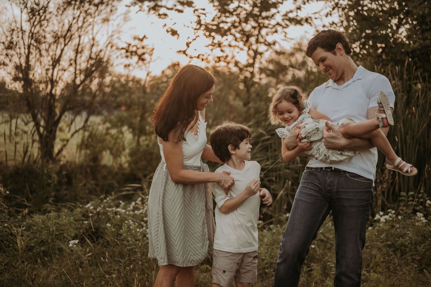 A family shares a tender moment together in a wildflower field at dusk.